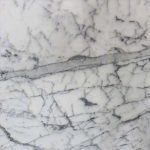 a Statueritto marble countertop that has think and thick veining over the white marble surface
