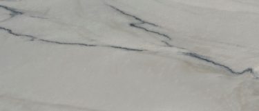 a Fantasy Macaubas quartzite countertop surface that features white and gray veins in a wavy pattern over the soft gray background