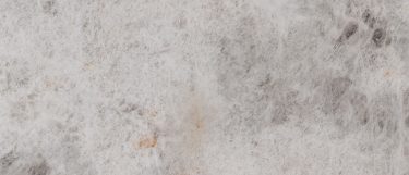a Cristallo quartzite countertop surface that features gray and orange flecking and veining details over the cool white background