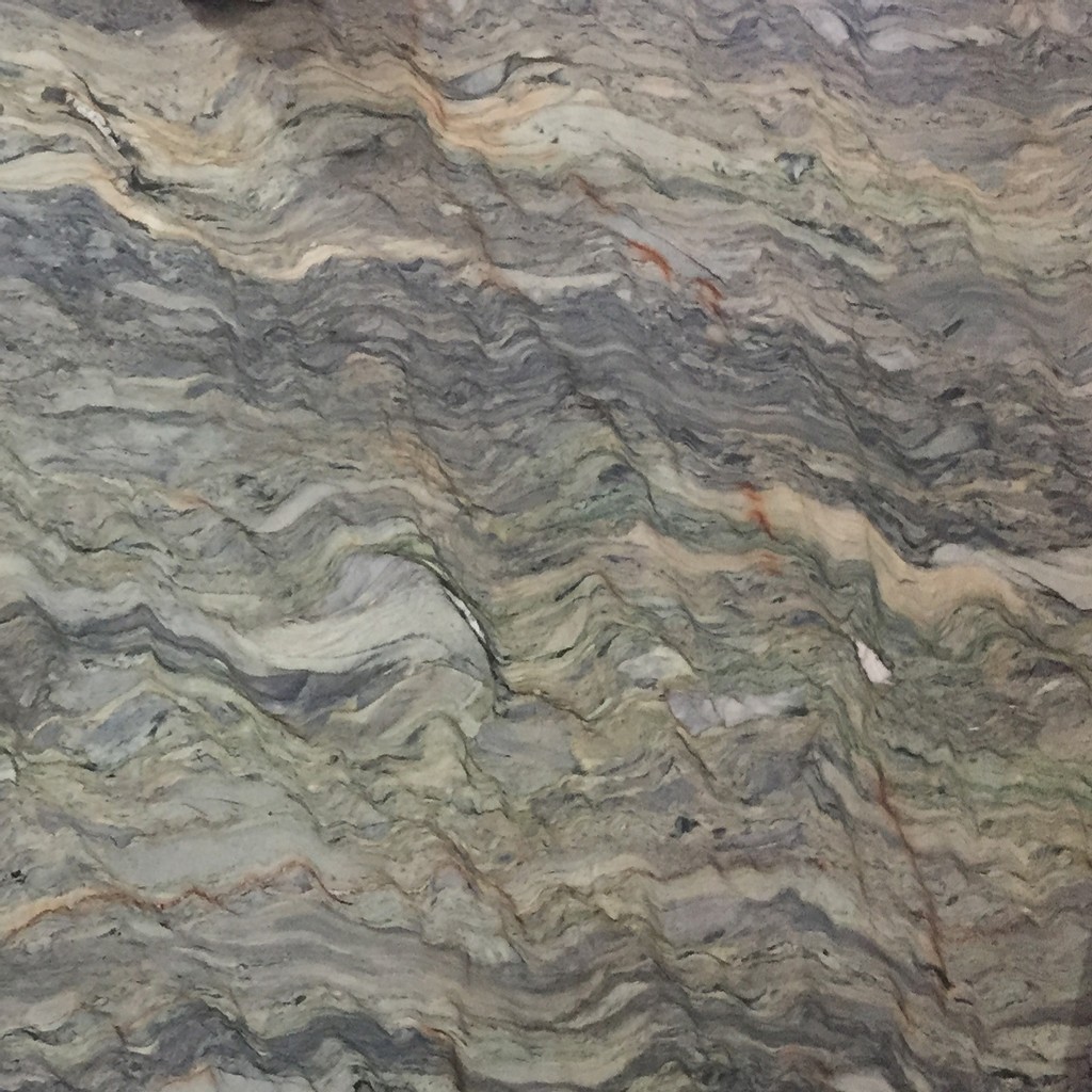 a Blue Fusion quartzite countertop surface that features shades of bluish gray, creams, and rust colors that are blended together in a swirling wavy pattern