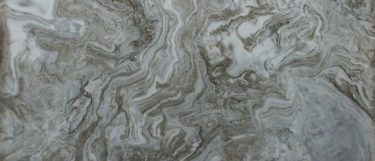 an Avalanche quartzite countertop surface that features swirls of creamy white and brown with gray vein details
