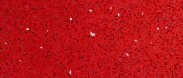 a sparkling red quartz countertop that has a speckled crimson red surface