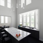 a kitchen with white cylinder pendant lighting fixtures, white painted walls, and Alaska Black countertops and kitchen island with a black cabinet base