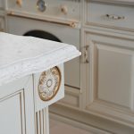 an Akoya countertop surface over the white base that has gold details