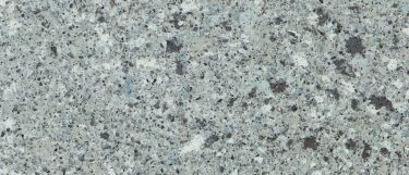 an Alpina White quartz countertop surface that features a pebbled-like pattern in gray, white, and brown over the creamy gray background