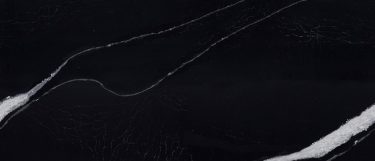 a Mersey quartz countertop surface that features a white streak design over the deep black background
