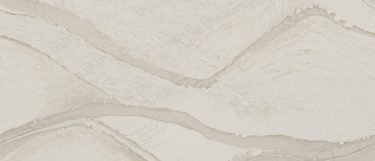a Brittanicca Warm quartz countertop surface that features translucent gray veins across the cream white background
