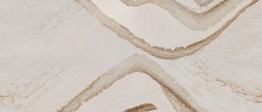 a Brittanicca Gold quartz countertop surface that features ash veins and charcoal speckles over the creamy marble background