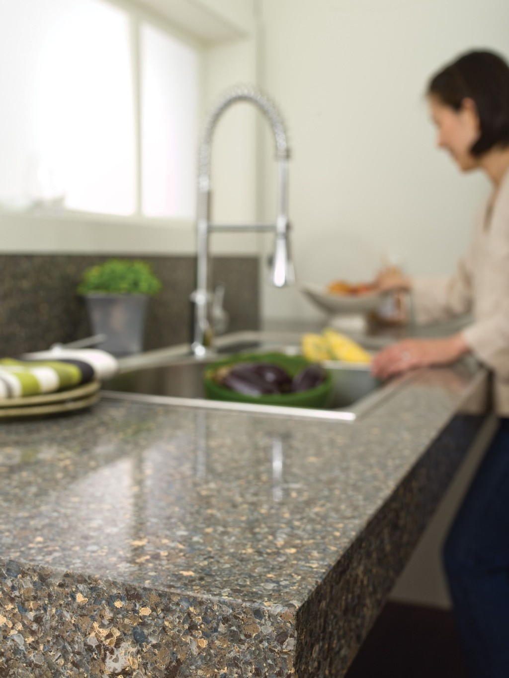 TN | Pro Stone Countertops a woman washing vegetables in a sink that is over the Bradford quartz countertop surface