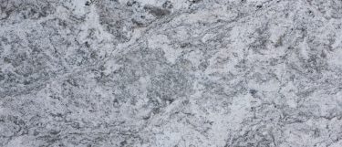 a white alamo granite countertop surface with gray and charcoal flecks and swirls on top of a white base color