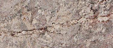 a white spring granite countertop with white, gray, and red swirls on top of its warm white background.