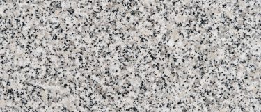 a Luna Pearl granite countertop surface that features pattern of white, black, gray, brown, and cream small speckles