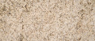 a Giallo Verona granite countertop surface that has a pattern of black, white, gold, and beige speckles