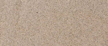 a Giallo Fantasia granite countertop surface that features fleck details in gold, dark brown, and gray over the cream background