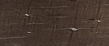 a Cygnus granite countertop surface that features black, ivory, and pearl linear veins over the brown background