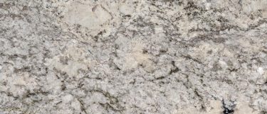an Alpine Valley granite countertop surface that features beige, black, and charcoal accents over the warm white background