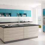 a kitchen with turquoise cabinetry with white kitchen ware displays, and Absolute black countertops and kitchen island with a wooden cabinet base over the white flooring