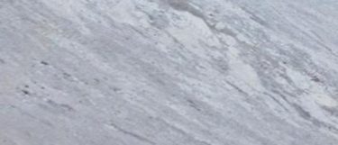 a Glacier white granite countertop surface that has light gray veins blended with swirls of ivory that has black dots throughout
