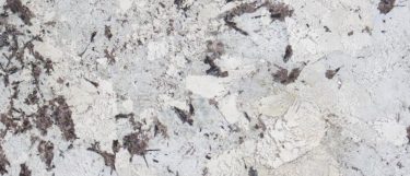 an Everest granite countertop surface that features splashes and spots of dark brown and tan over the off-white background