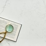 a magnifying glass and a book over the Alabaster White quartz countertop surface