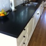 a kitchen counter with Absolute Black countertops and white cabinet base over the hardwood flooring
