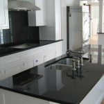 a kitchen with white cabinetry and Absolute Black granite countertops and kitchen island