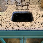 a sink over the Vail Village Quartz countertop above the turquoise cabinet base with silver hardware