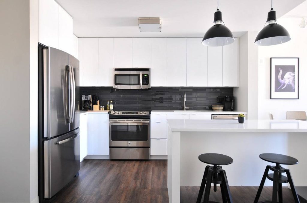 a kitchen with dark brown wooden floors and countertops, cabinets, and walls in white and black details in  the chairs, lighting fixtures, and backsplash