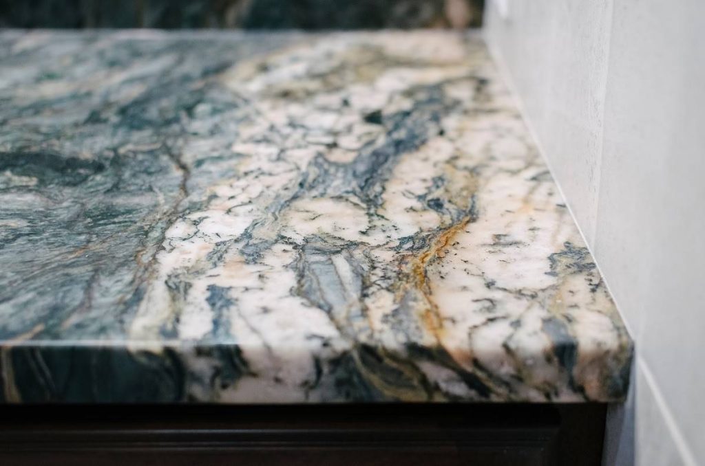 a countertop corner with bold veins in varying colors of gold, black, gray, beige, and blue that creates a unique pattern on the stone surface