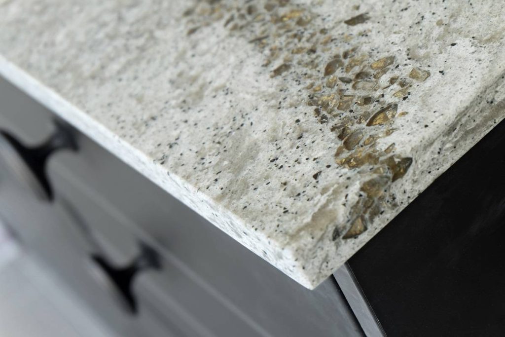 an overhang edge of a cool toned ivory countertop with gold, grays, and black details