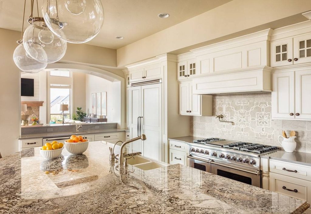a clean kitchen that features beige countertop with sink, white cabinets, creamy beige walls, a stove, and other decorative displays