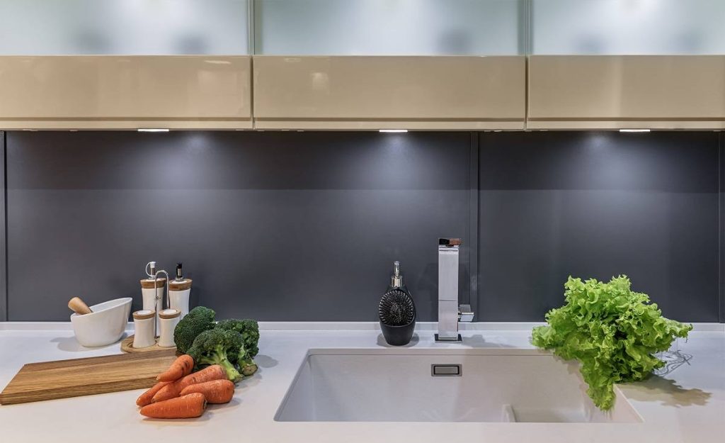 a modern kitchen in high-tech style with sliding door cabinetry, under cabinet lighting, and a countertop with vegetables all over its surface