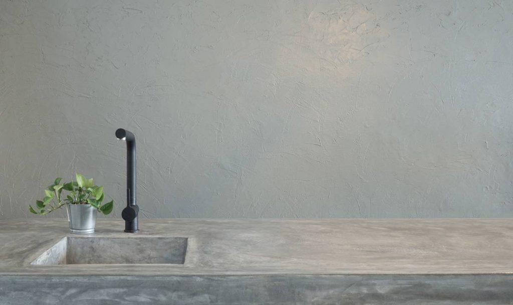a modern black faucet and kitchen sink over the cement finished countertop