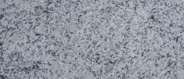 a white napoli granite countertop surface with detail accents in black, gray, and cream over its cool white background