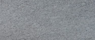 a white ornamental granite countertop surface with little specks and traces of cream, beige, black, and gray speckles over its cool white base