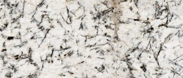 a white glimmer granite countertop surface with striking brown and black veins and specks against a warm white background