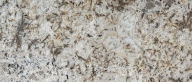 a granite countertop surface that has a warm white background, and flecks and veins ranging from cream, brown, to black
